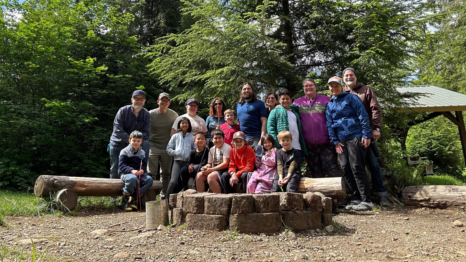 Scouts and parents from Pack 426 gathered around a campfire ring in the woods on a spring outing.