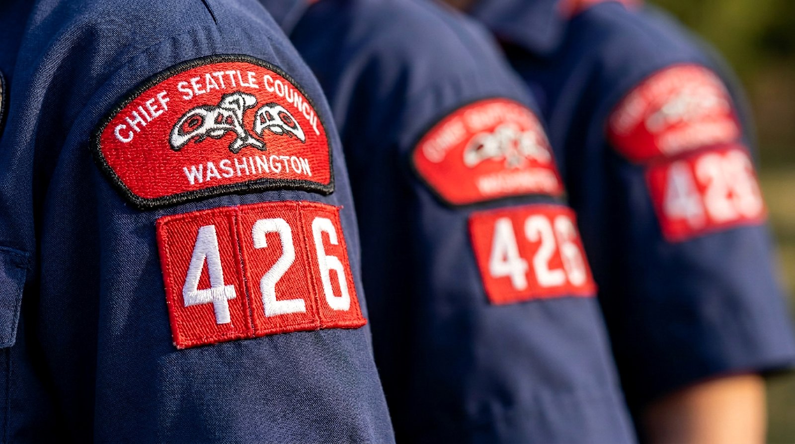 Close detail of Cub Scout uniform sleeves showing the Chief Seattle Council patch above red and white 426 unit numerals.